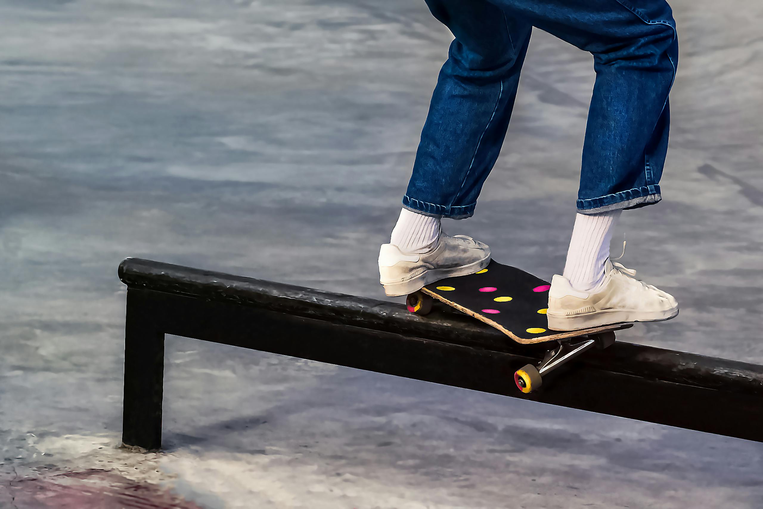 Close-up of skateboarder performing a trick on a metal railing at an outdoor skatepark.