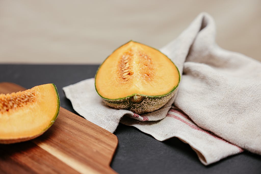 10 Foods You’re Not Eating That Could Be Secretly Causing Dehydration 3 Close-up of sliced cantaloupe on a wooden board with linen cloth, highlighting fresh textures.