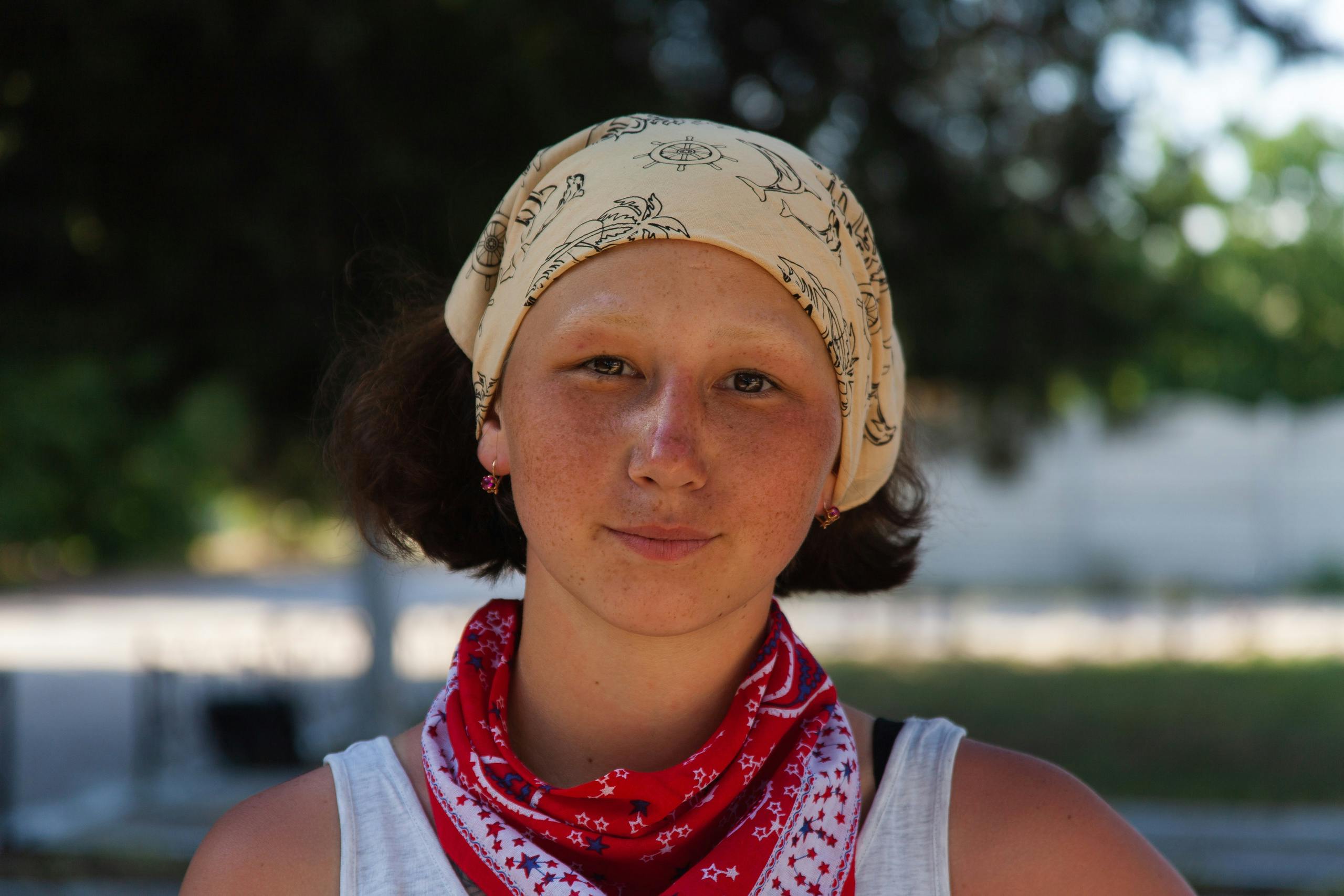 Close-up portrait of a young woman wearing a bandana, captured in natural light outdoors.