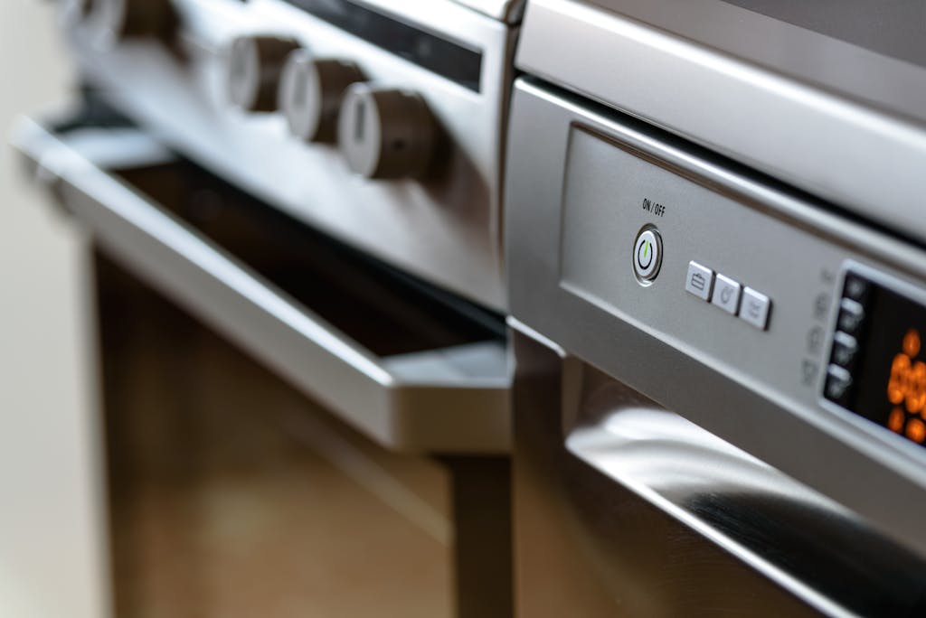 8 Repairs That Can Push You into Debt Before You Even Realize It 4 Close-up view of modern stainless steel kitchen appliances with focus on dishwasher and oven.