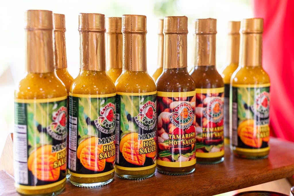 Colorful assortment of Trinidadian mango and tamarind hot sauces in bottles.