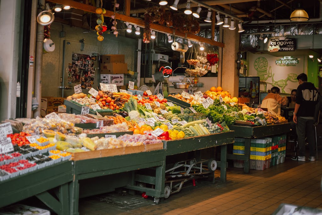 8 Foods That Completely Ruined My Grocery Budget 1 Colorful indoor market stall with an array of fresh fruits and vegetables on display.
