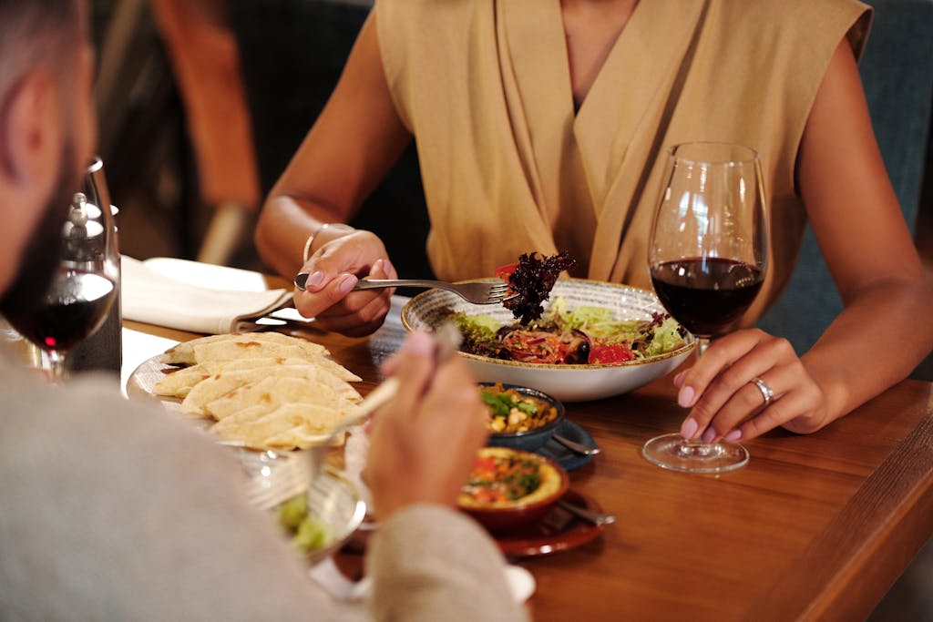 Couple enjoying a romantic dinner with wine and delicious meals at a cozy restaurant.