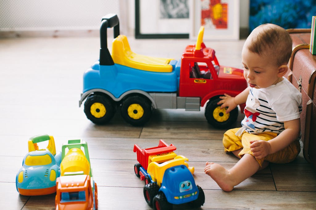 Cute baby boy enjoying playtime with vibrant toy trucks indoors