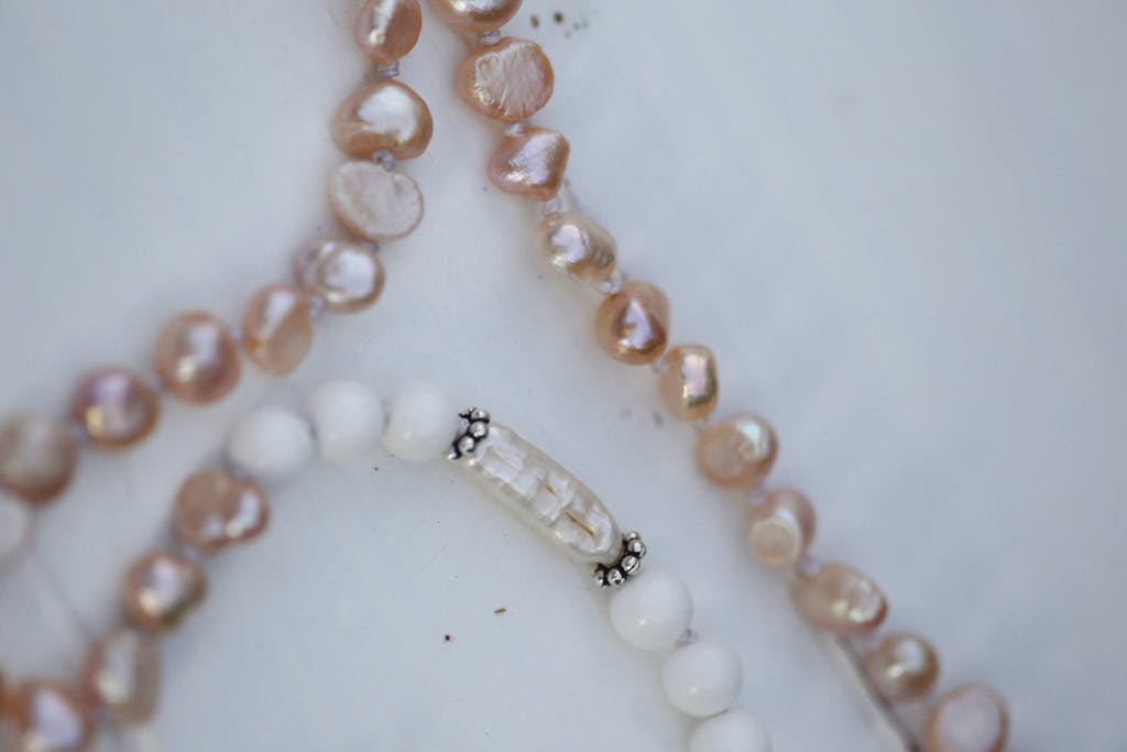 Delicate close-up of pink and white beaded pearl necklaces on a light background.