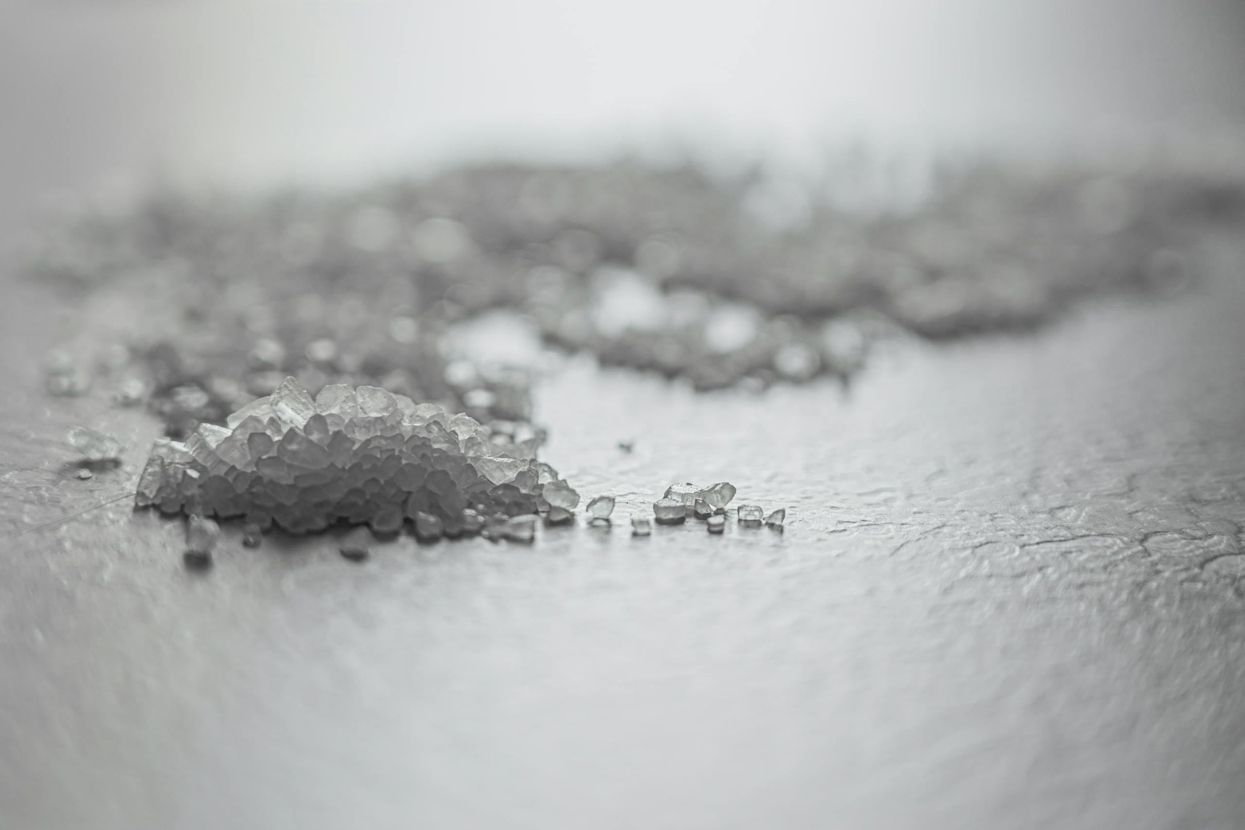 Detailed shot of coarse rock salt scattered on a textured surface.