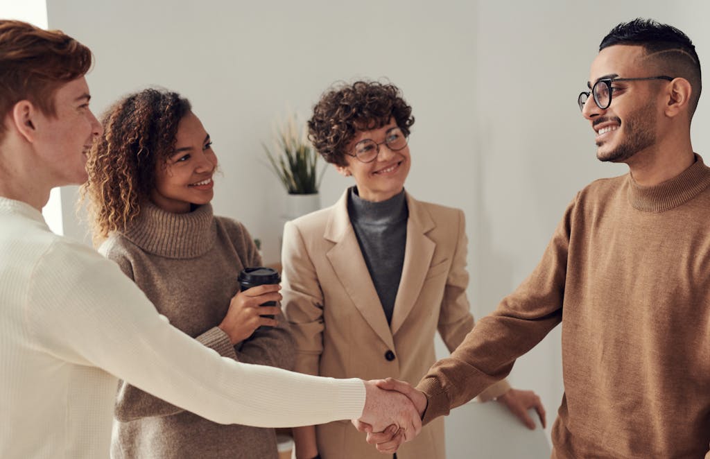 Most People Over 40 Who Lack These 9 Skills Are Struggling in Silence 2 Diverse group of young adults shaking hands in an office environment, depicting teamwork and collaboration.