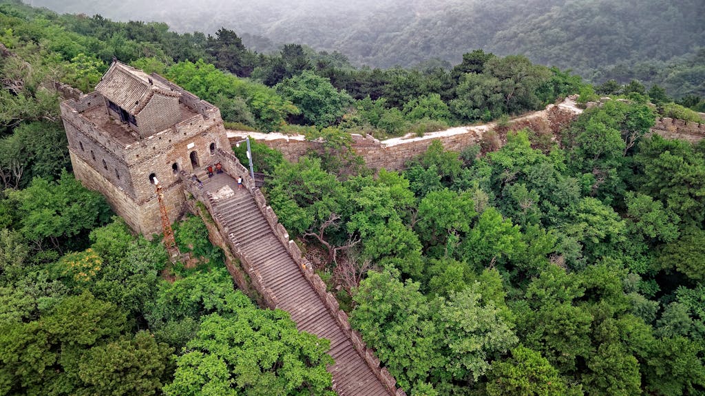Drone shot of the Great Wall of China amidst lush greenery in Huairou, Beijing.
