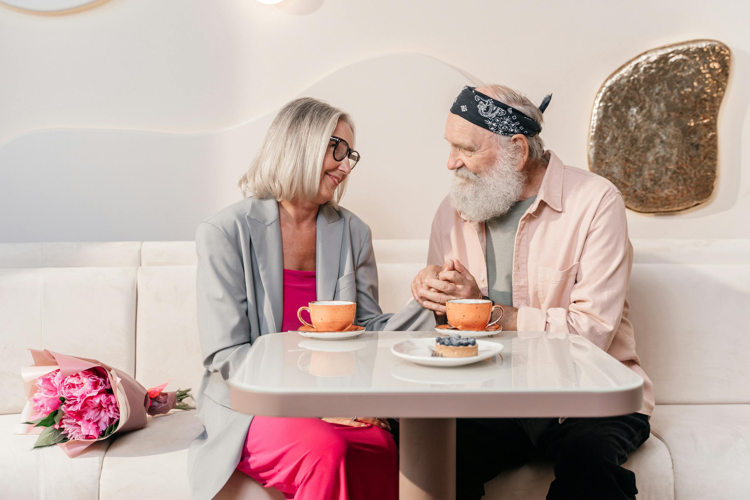 Elderly couple sharing a romantic moment over coffee, holding hands in a cozy cafe.