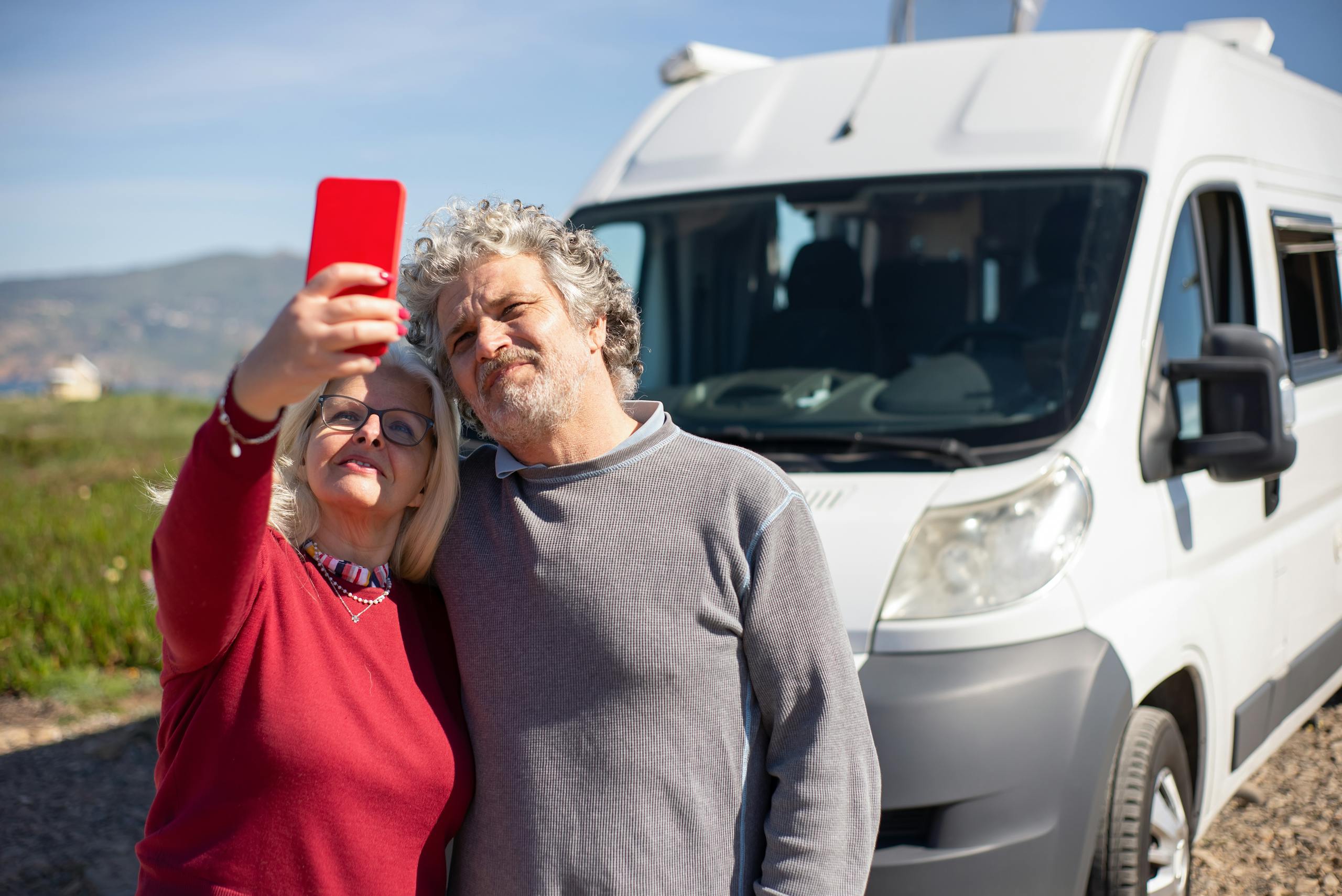 Elderly couple taking a selfie during a campervan road trip in sunny Portugal.