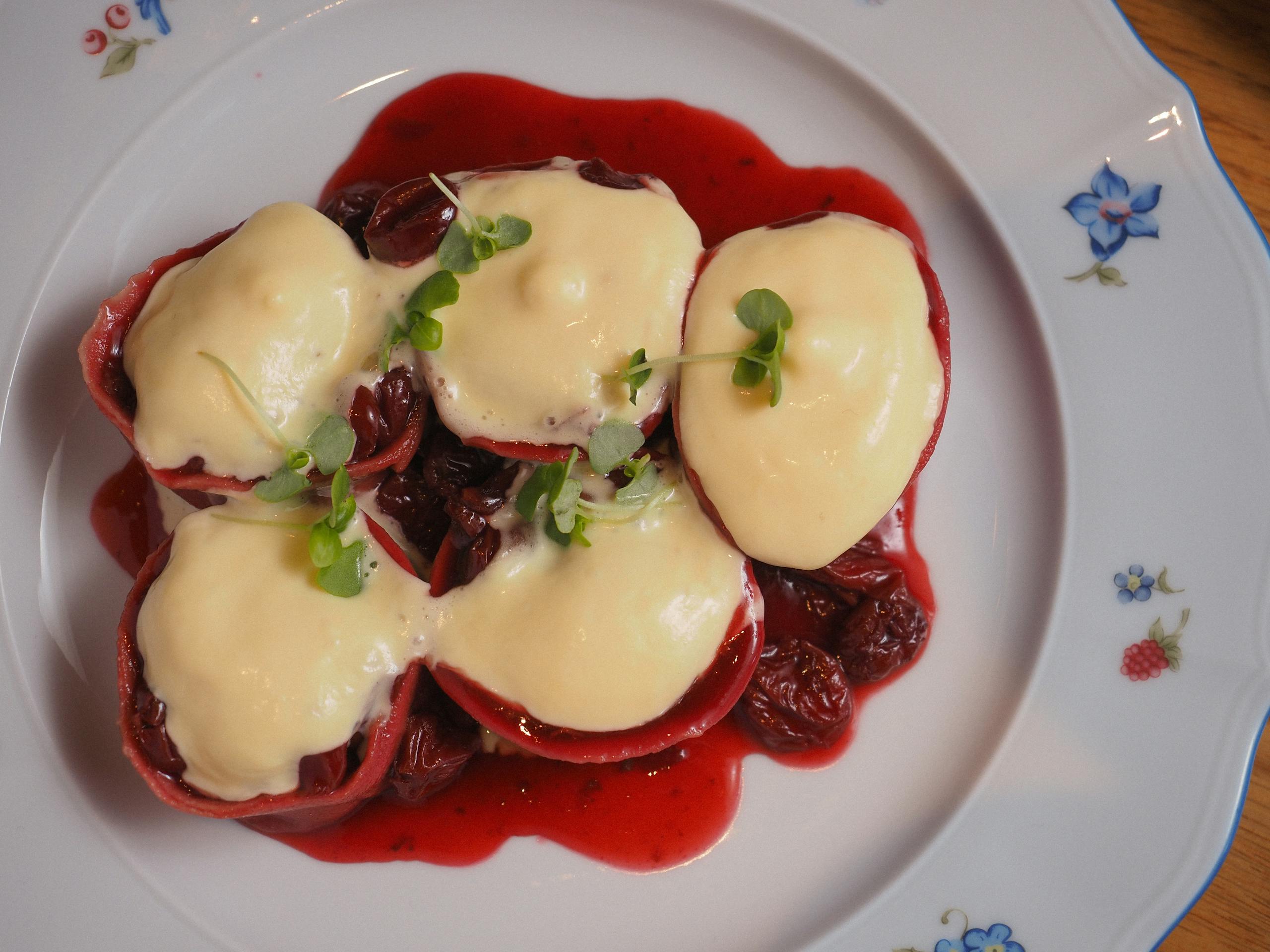 Elegant dish of ravioli with creamy topping on a decorative plate.