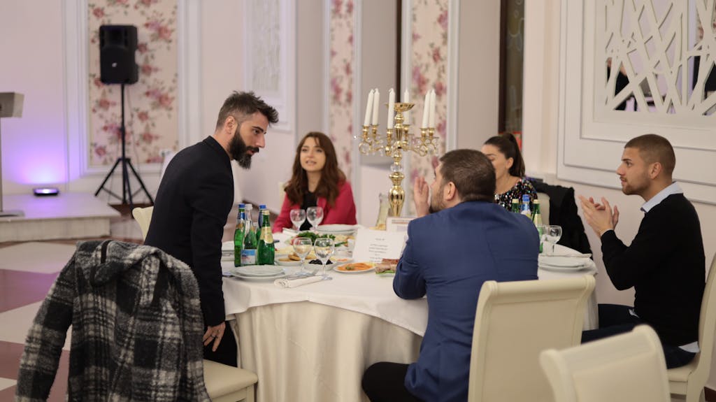 Elegant indoor dinner gathering with diverse group discussing and enjoying drinks, creating a warm social atmosphere.