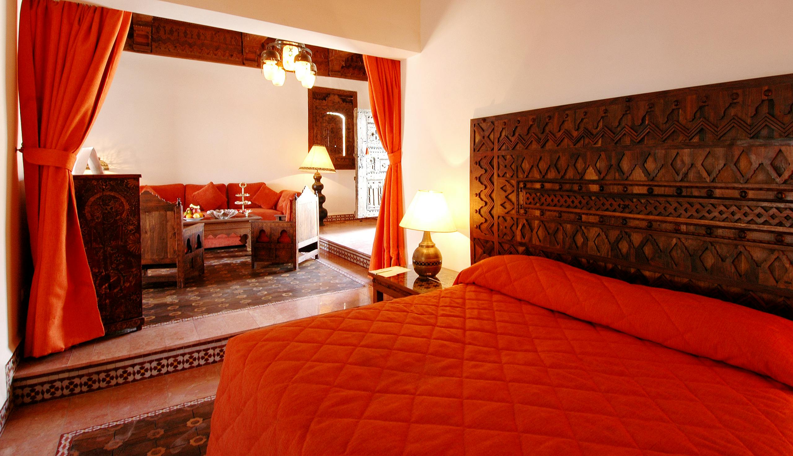 Elegant Moroccan styled bedroom with vibrant orange decor and ornate woodwork.