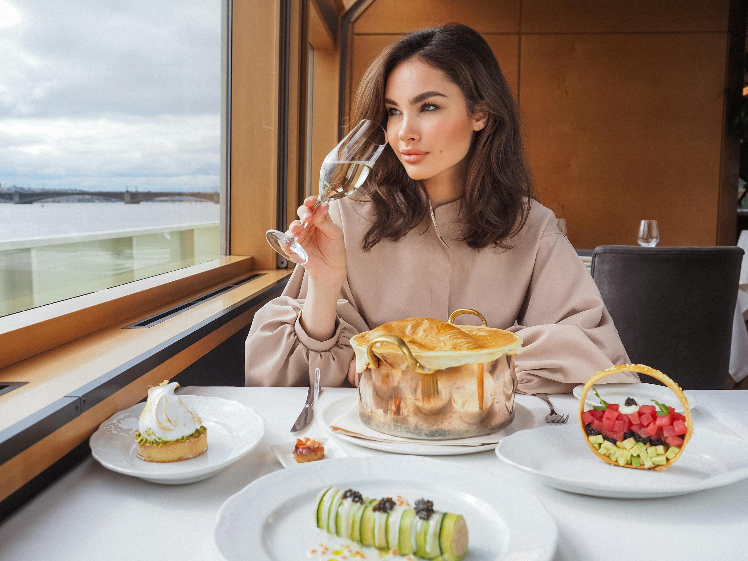 Elegant woman savoring wine during a gourmet meal on a luxury cruise, with sea views.