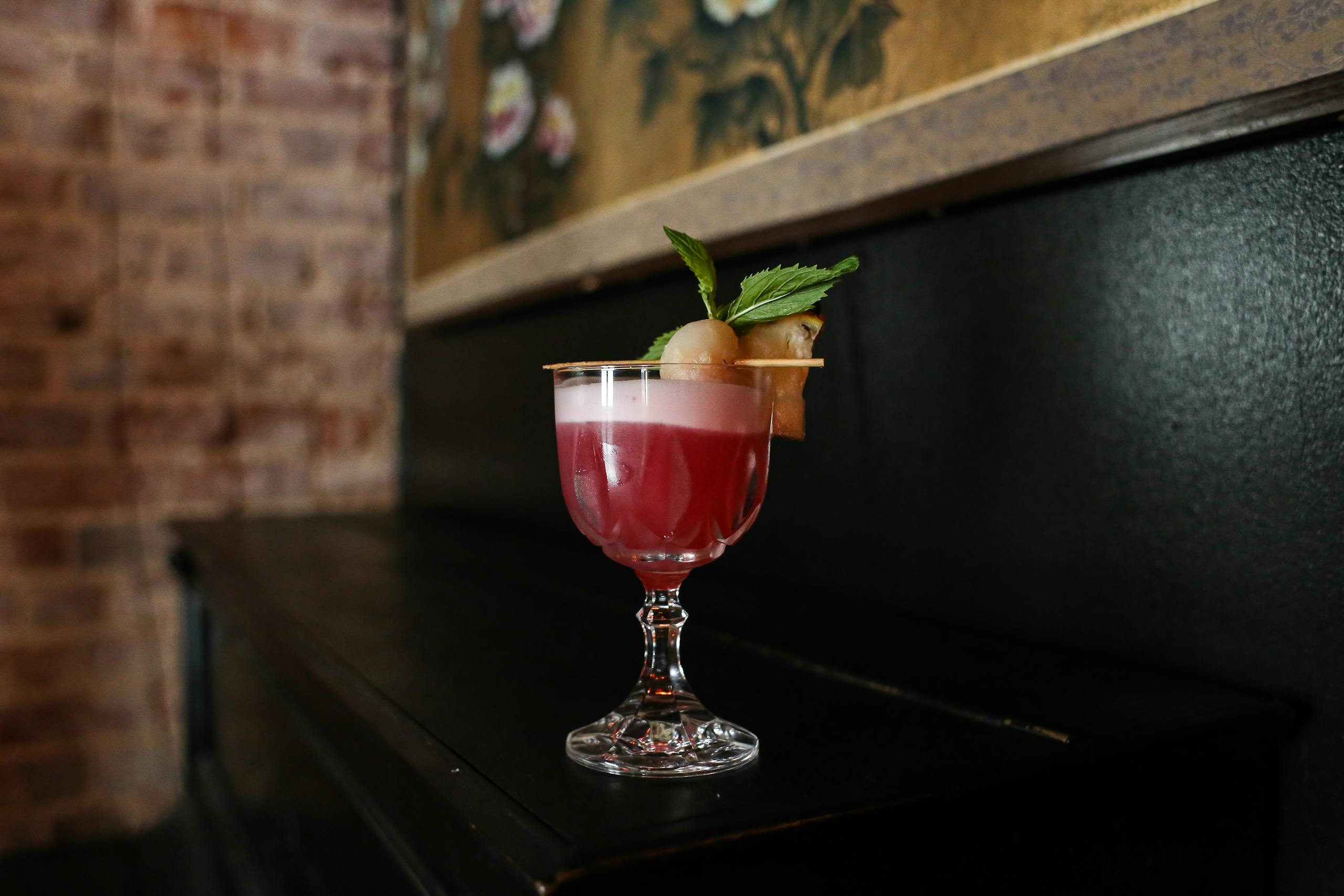 Exquisite berry cocktail in a delicate glass, garnished with mint leaves and fruit, elegantly set on a wooden table