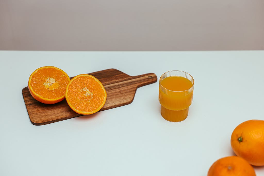 10 Foods You’re Not Eating That Could Be Secretly Causing Dehydration 5 Freshly squeezed orange juice with sliced oranges on a wooden board, perfect for a healthy diet.