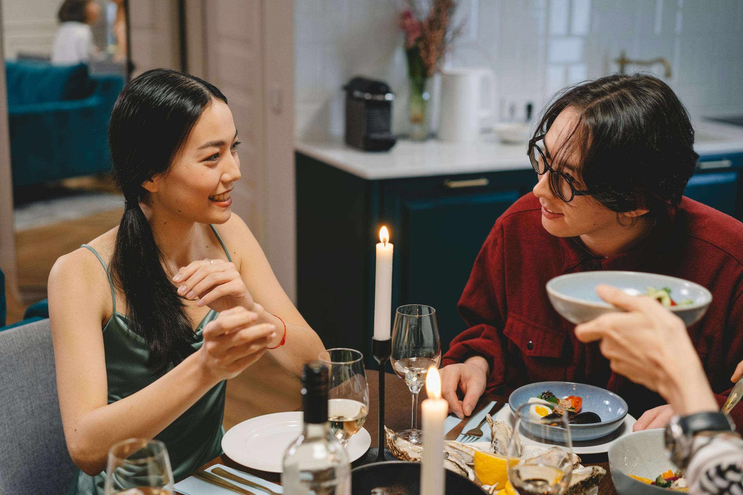 Friends enjoying a warm and friendly dinner conversation at a cozy table setting.