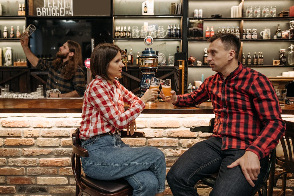Friends enjoying drinks and conversation in a cozy bar setting, wearing checkered shirts.