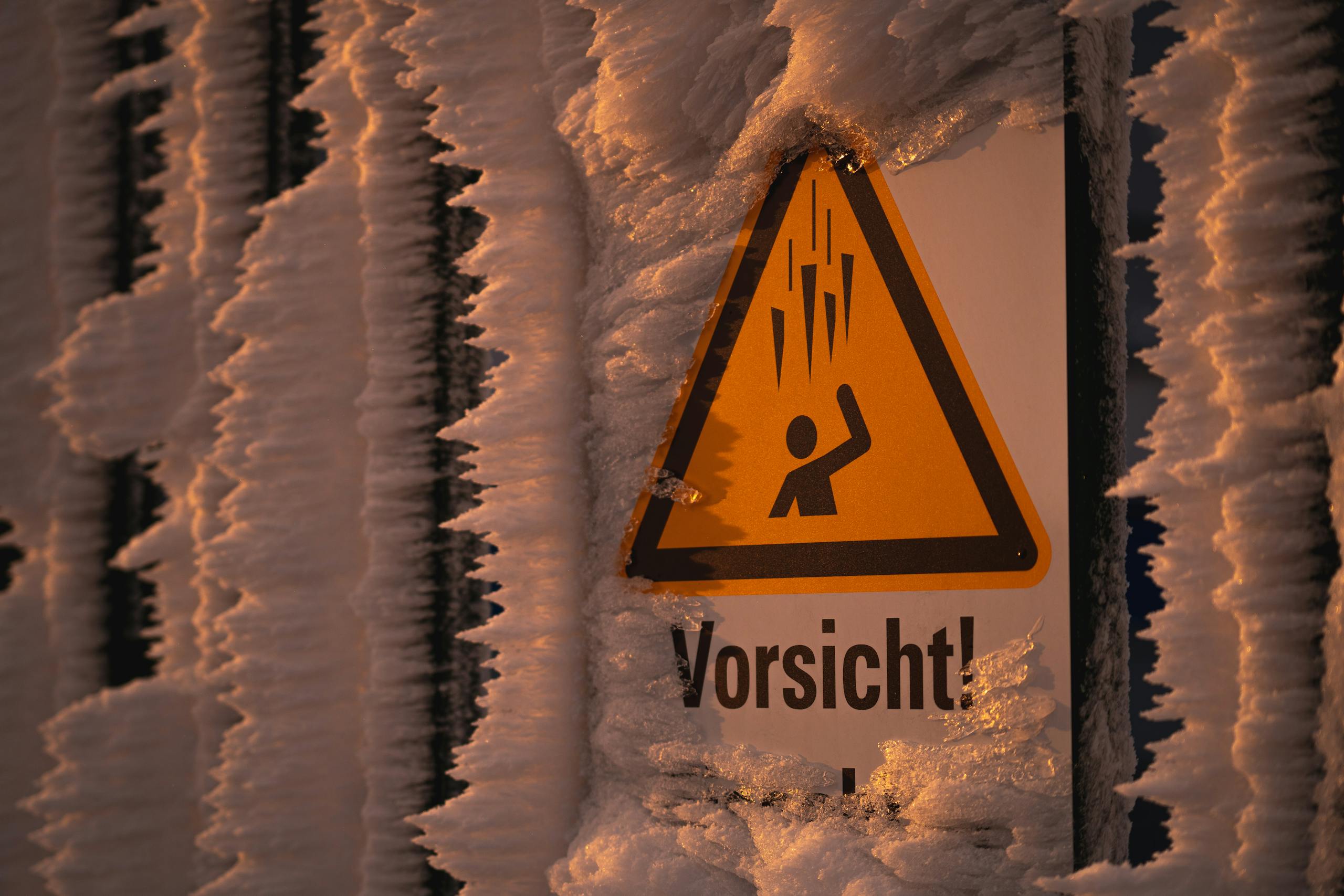 Frozen caution sign covered in ice and frost on a winter day.