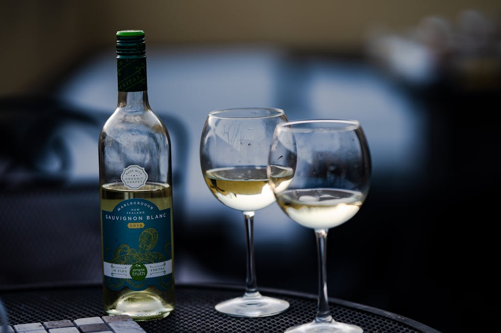 Glass bottle of wine placed near crystal wineglasses on round table in cafe