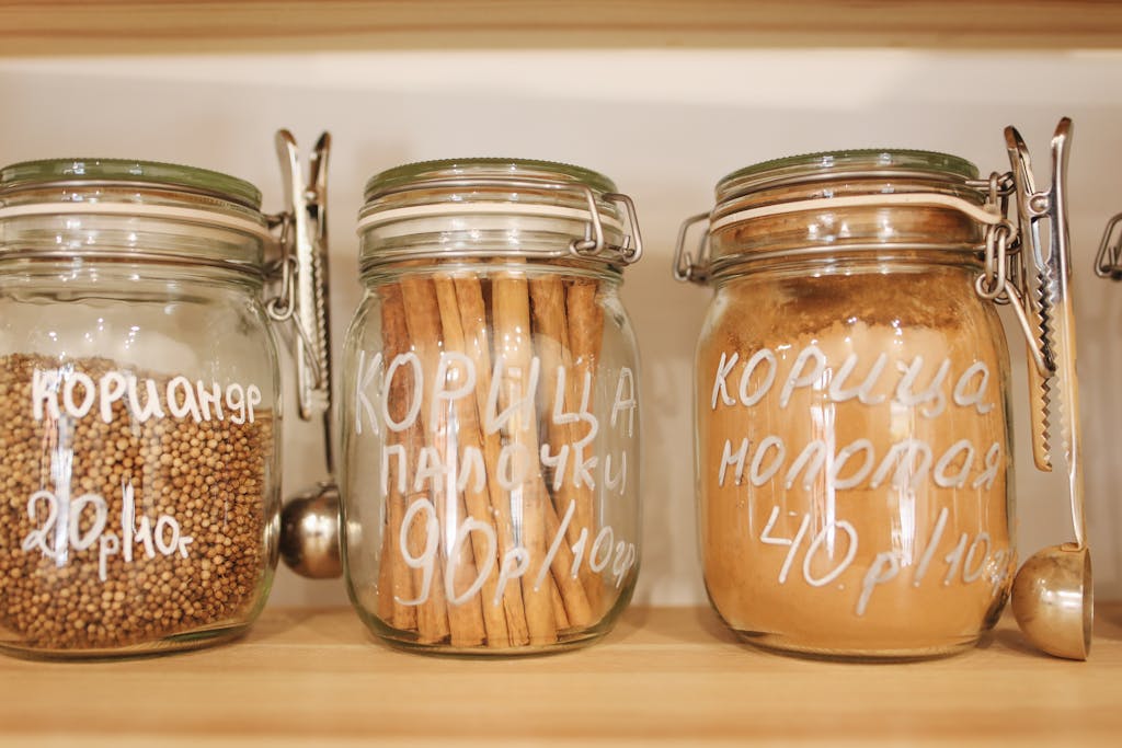 Glass jars on wooden shelves containing various spices, promoting zero waste and ethical shopping.