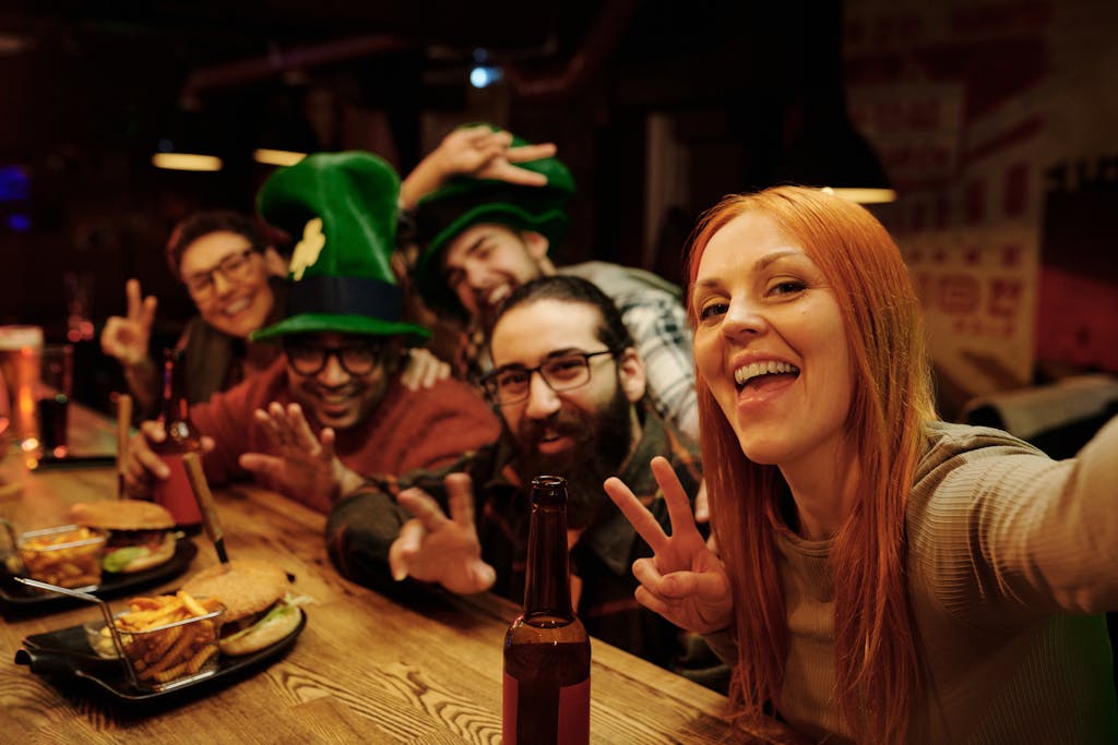 Group of friends enjoying St. Patrick's Day celebration at a bar with festive hats and drinks.