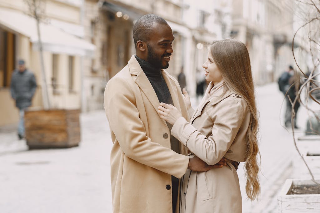 Happy interracial couple embracing outdoors in stylish winter clothing, expressing love and togetherness.