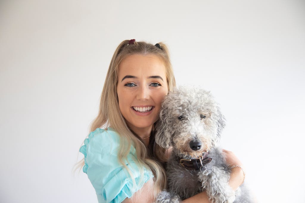 Happy woman with her cute Bedlington Terrier dog on a light background.