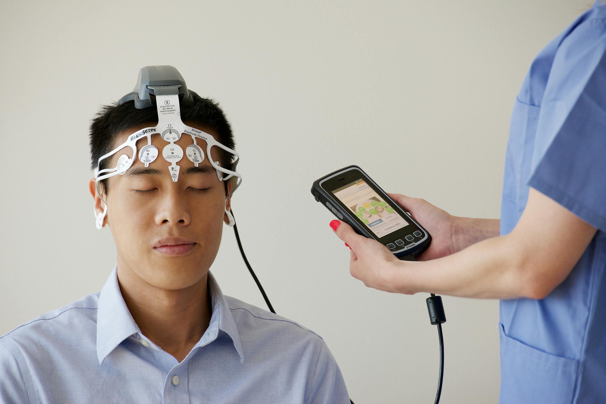 Healthcare professional conducting an EEG examination using a Brainscope device on a male patient.