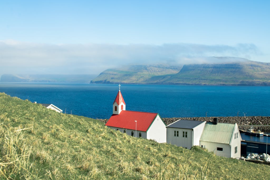 Idyllic coastal village view in Faroe Islands with traditional church and ocean backdrop.