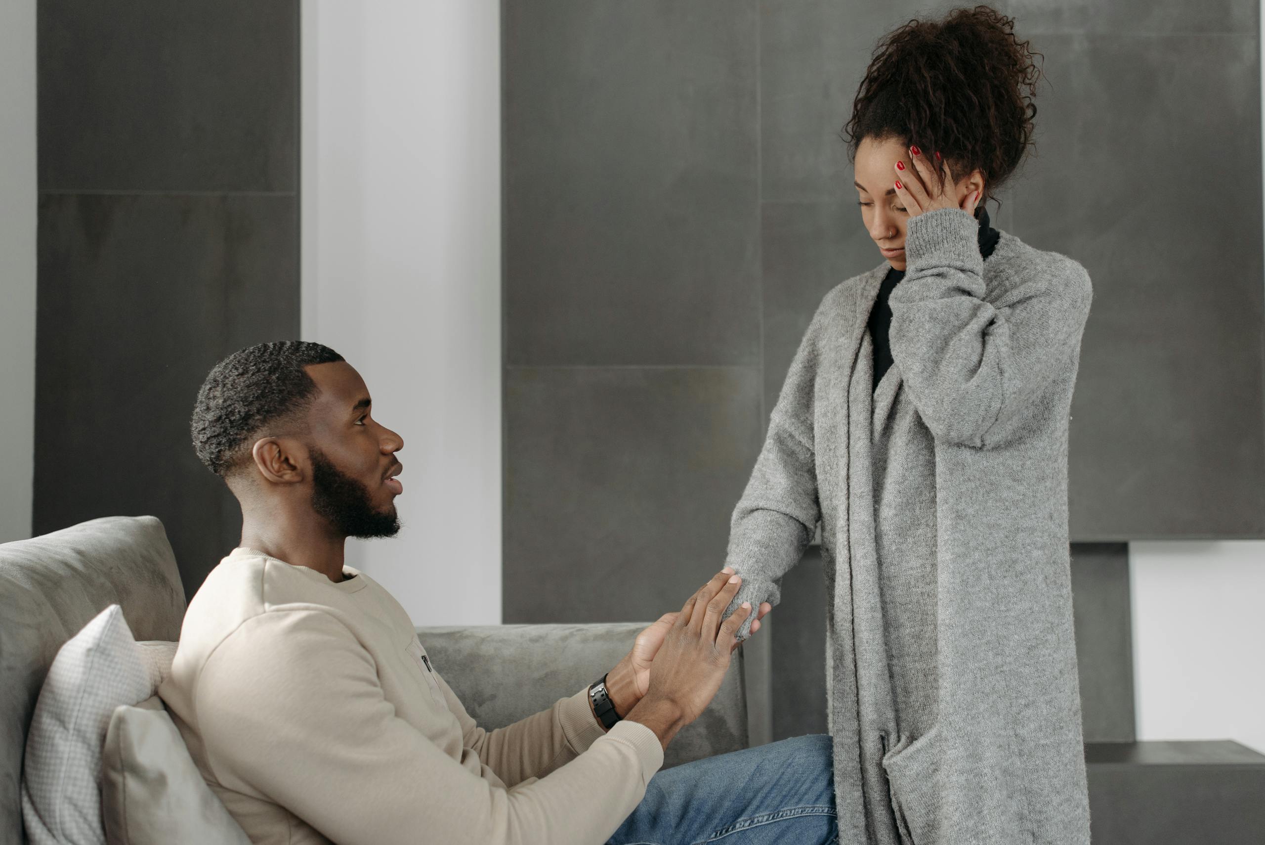 Man comforting woman with headache while sitting on a sofa indoors. Warm and supportive interaction.