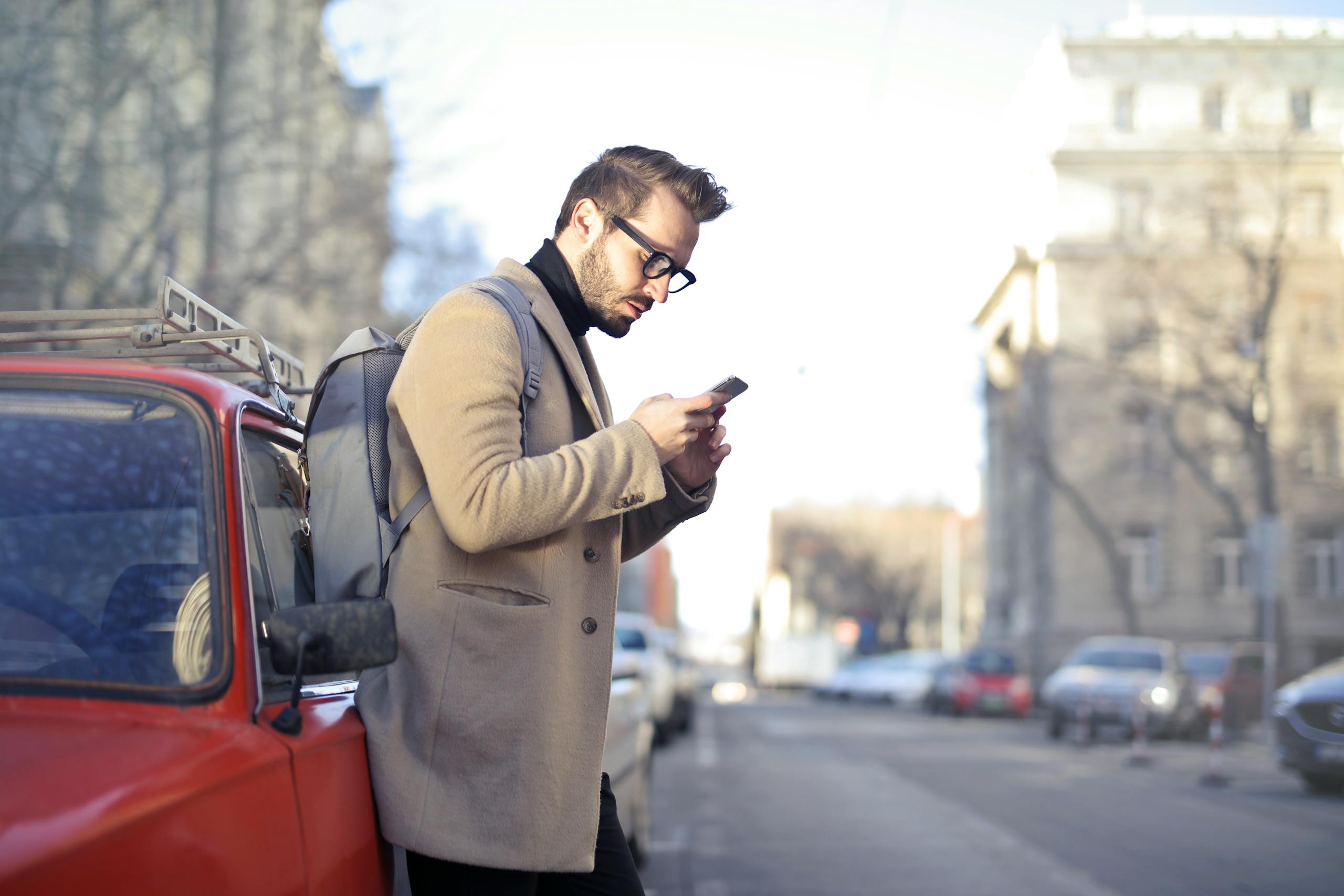 Man with backpack using smartphone on urban street in Budapest.