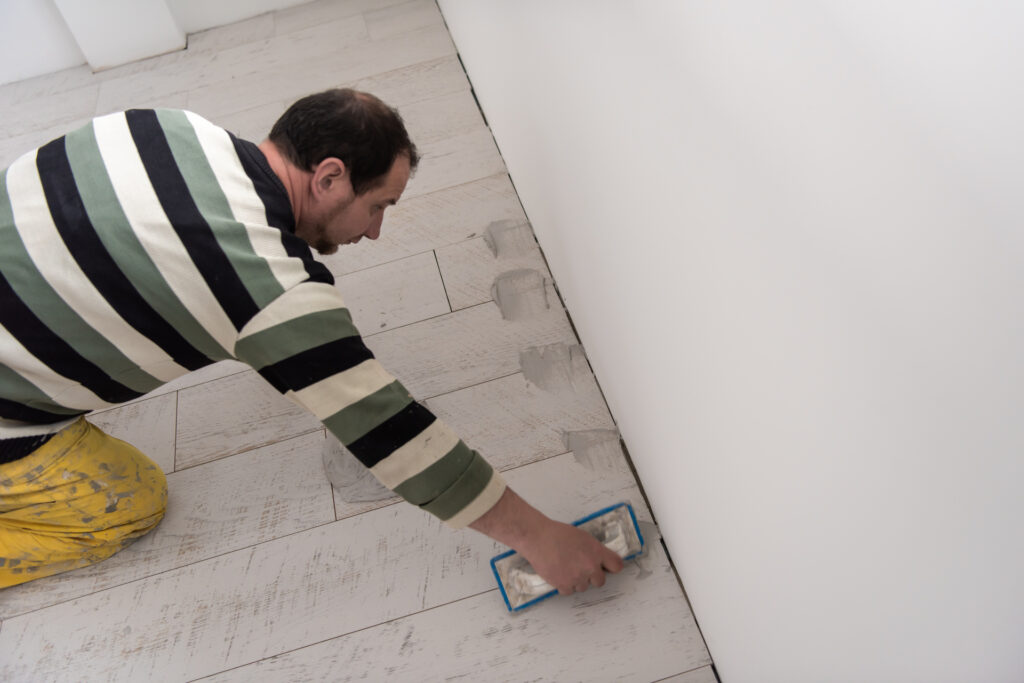 9 Home Maintenance Mistakes That Are Quietly Draining Your Wallet 1 medium vecteezy tilers filling the space between ceramic wood effect tiles 11949998 medium