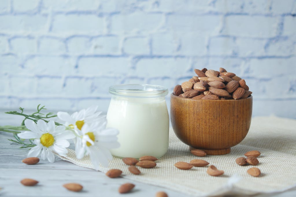 10 Superfoods That Could Be Damaging Your Health 3 Natural almonds in a wooden bowl with a glass jar of milk and white chamomile flowers on a wood table.