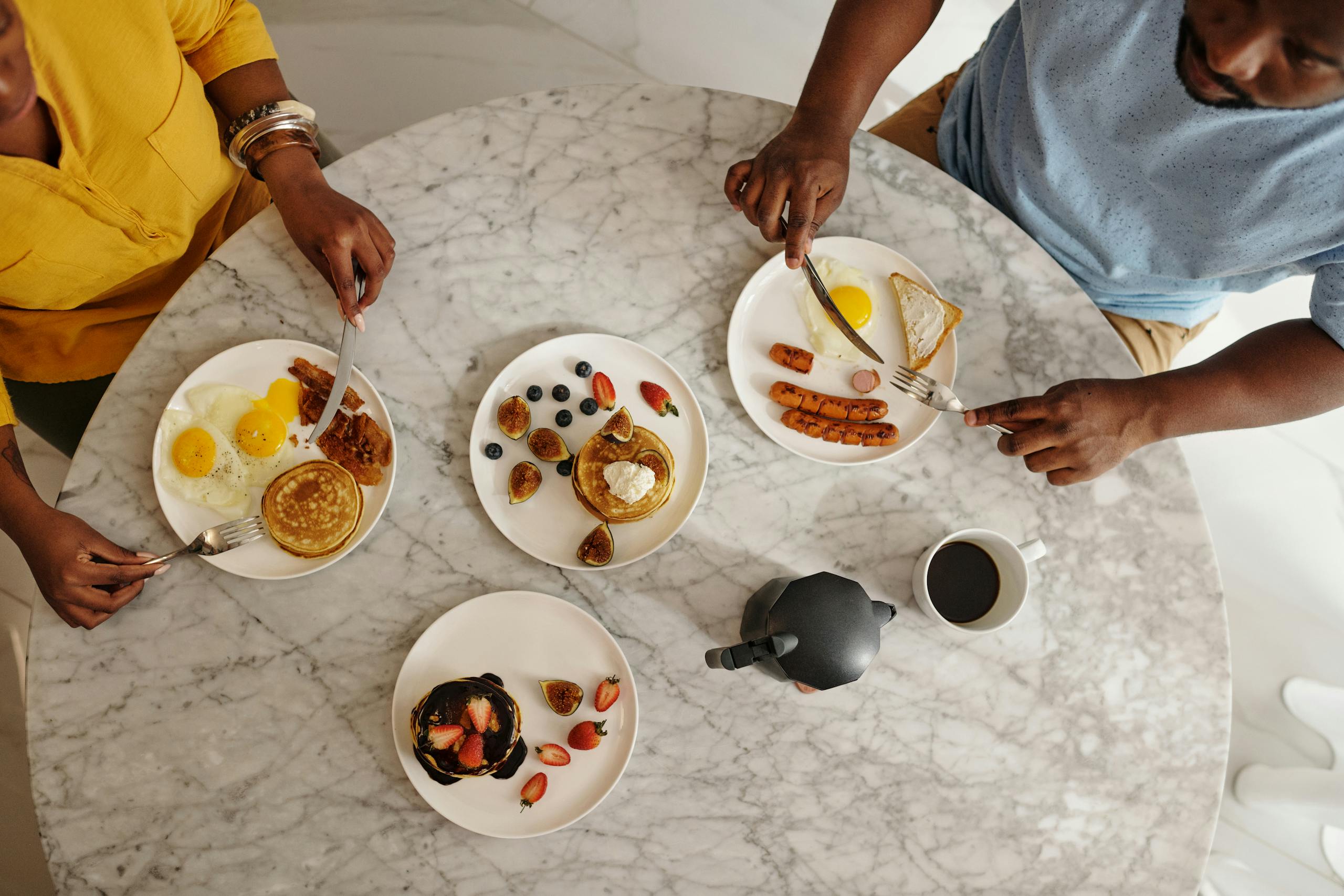 Overhead shot of a couple having a delicious breakfast with pancakes and coffee.