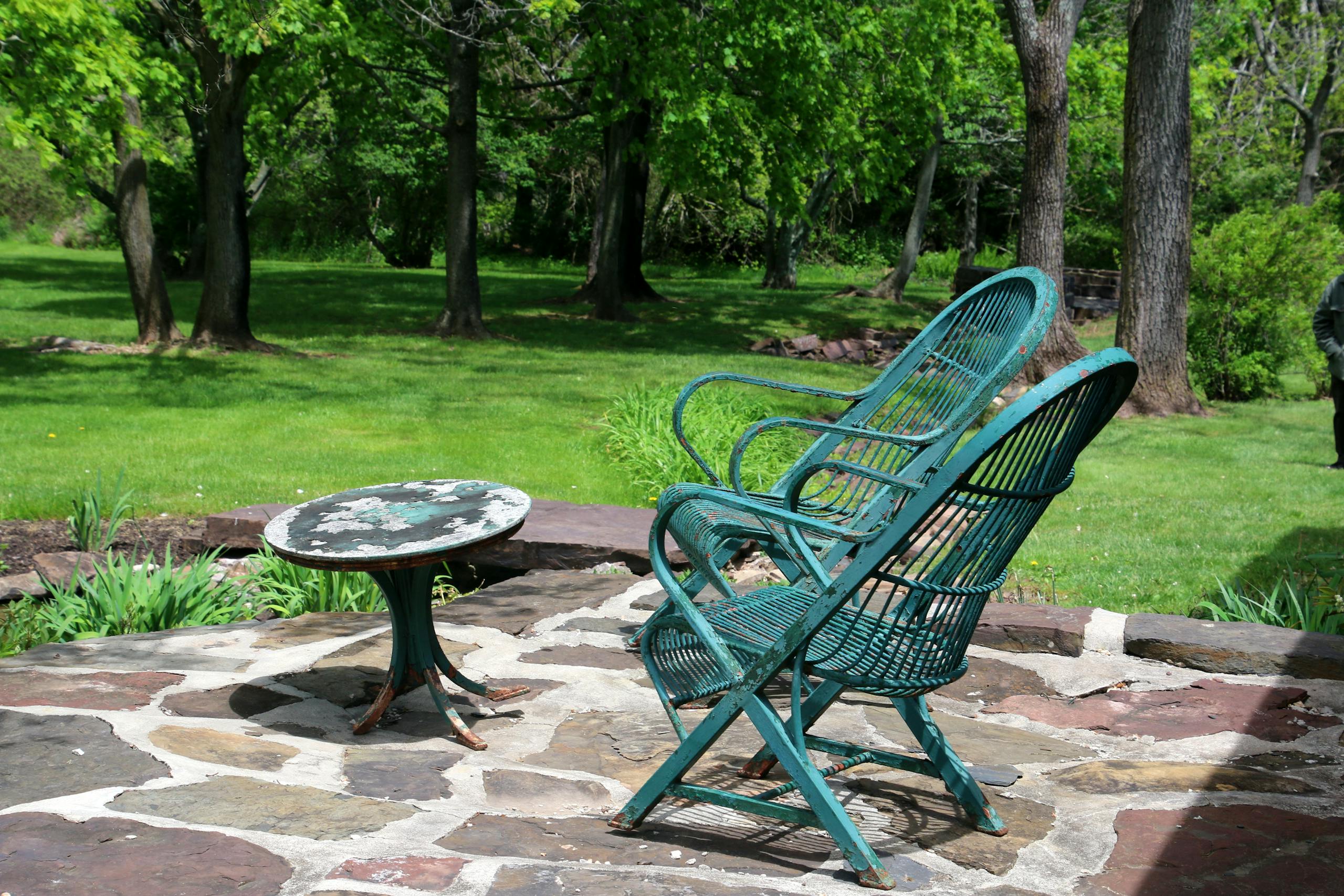 Peaceful outdoor seating area with metal chairs and table in a green garden.