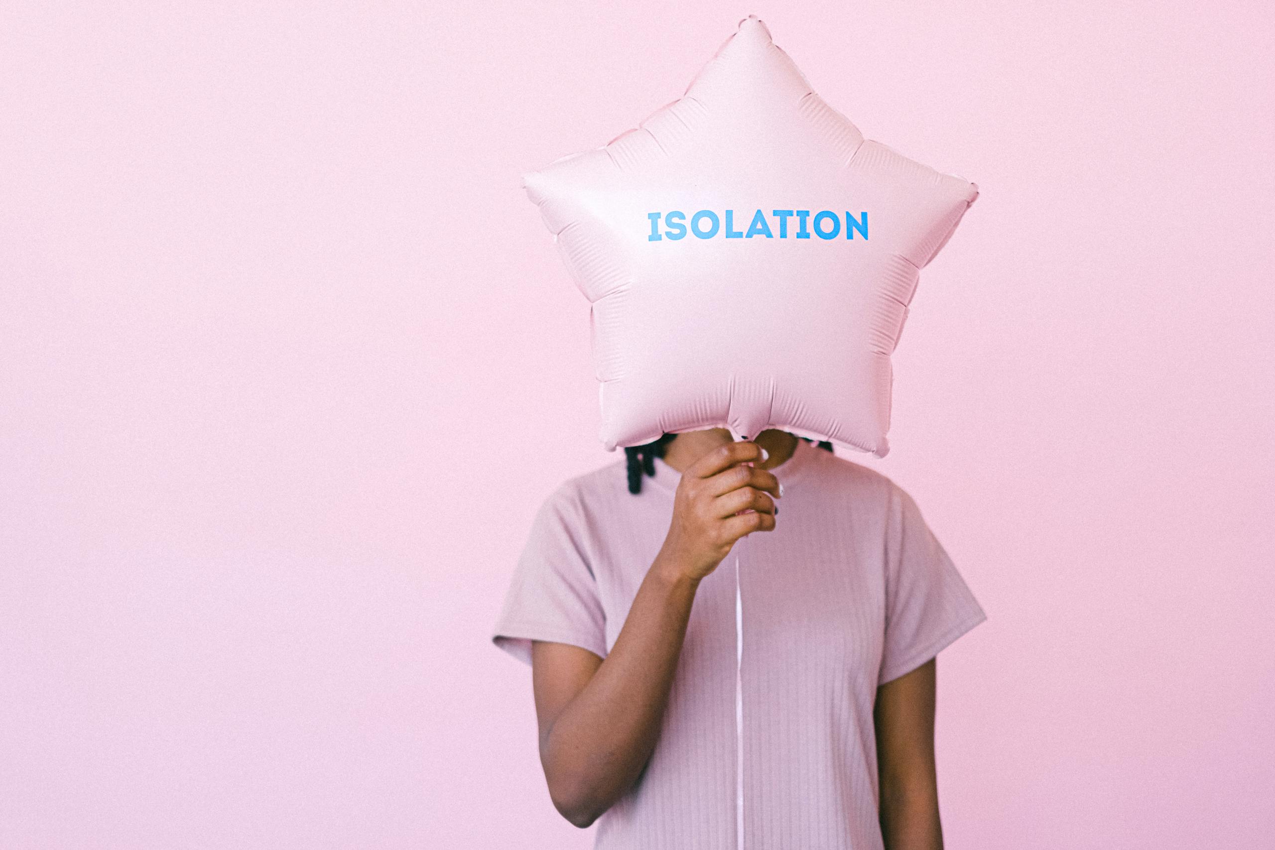 Person holding a star-shaped balloon with 'isolation' text on a light pink background.