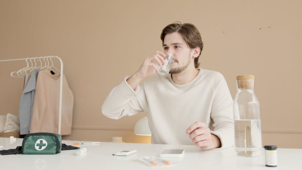 a-man-in-white-long-sleeves-sitting-while-drinking-water-