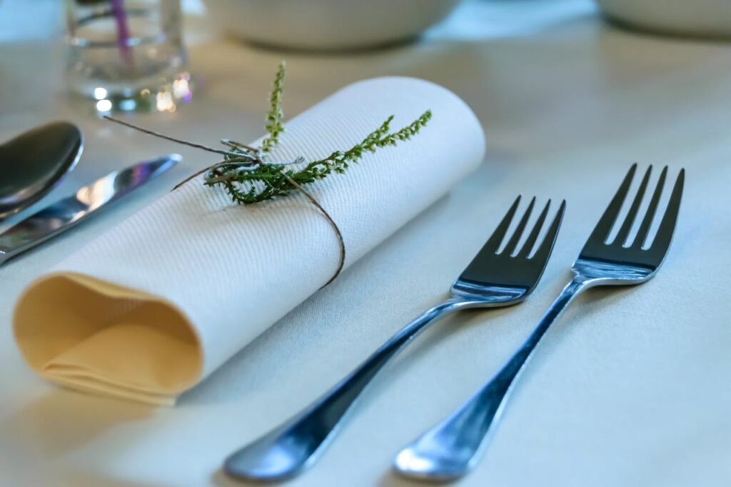 /stainless-steel-fork-beside-rolled-paper-towel-with-parsley-on-top-