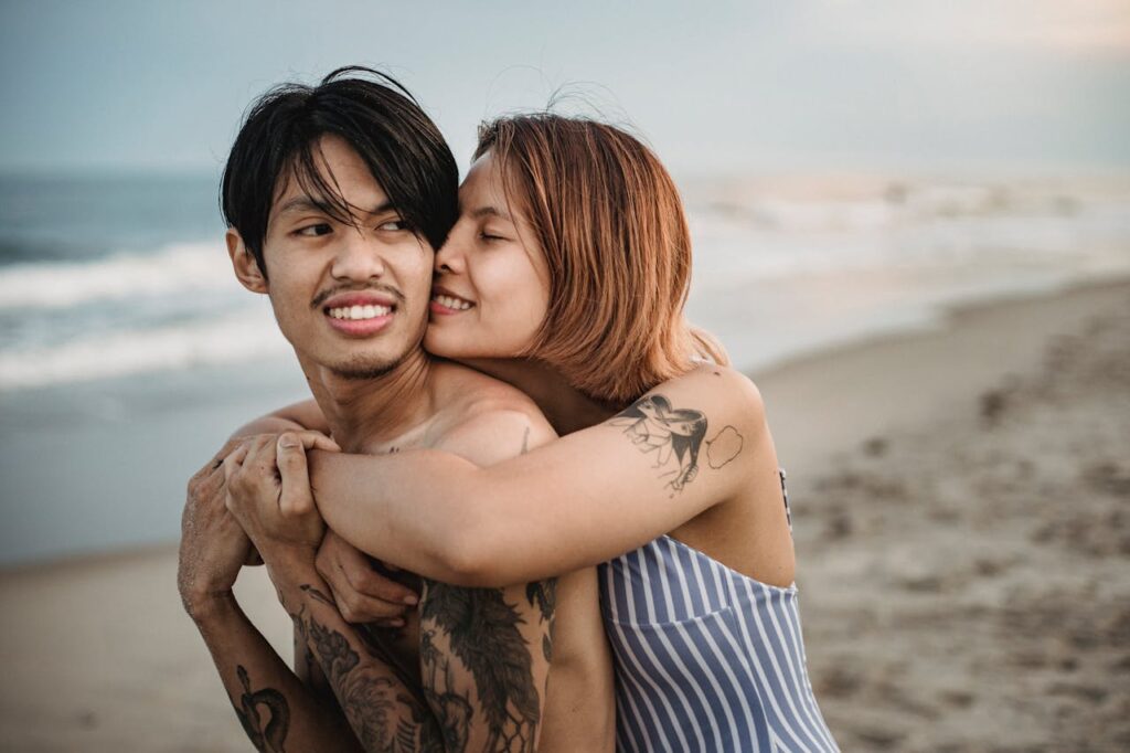 /woman-in-stripe-swimsuit-hugging-tattooed-man-