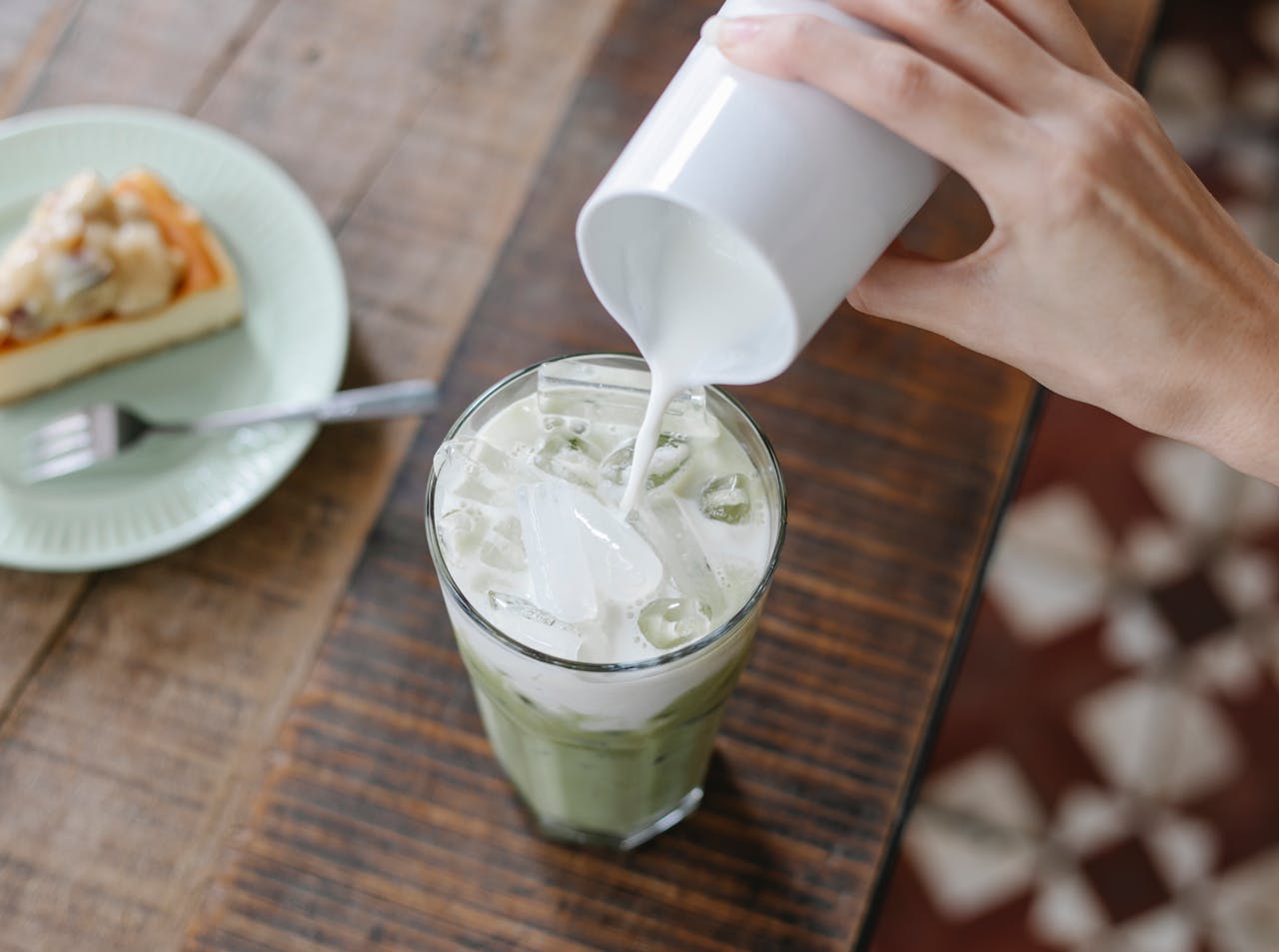 crop-unrecognizable-woman-adding-milk-to-iced-matcha-tea-