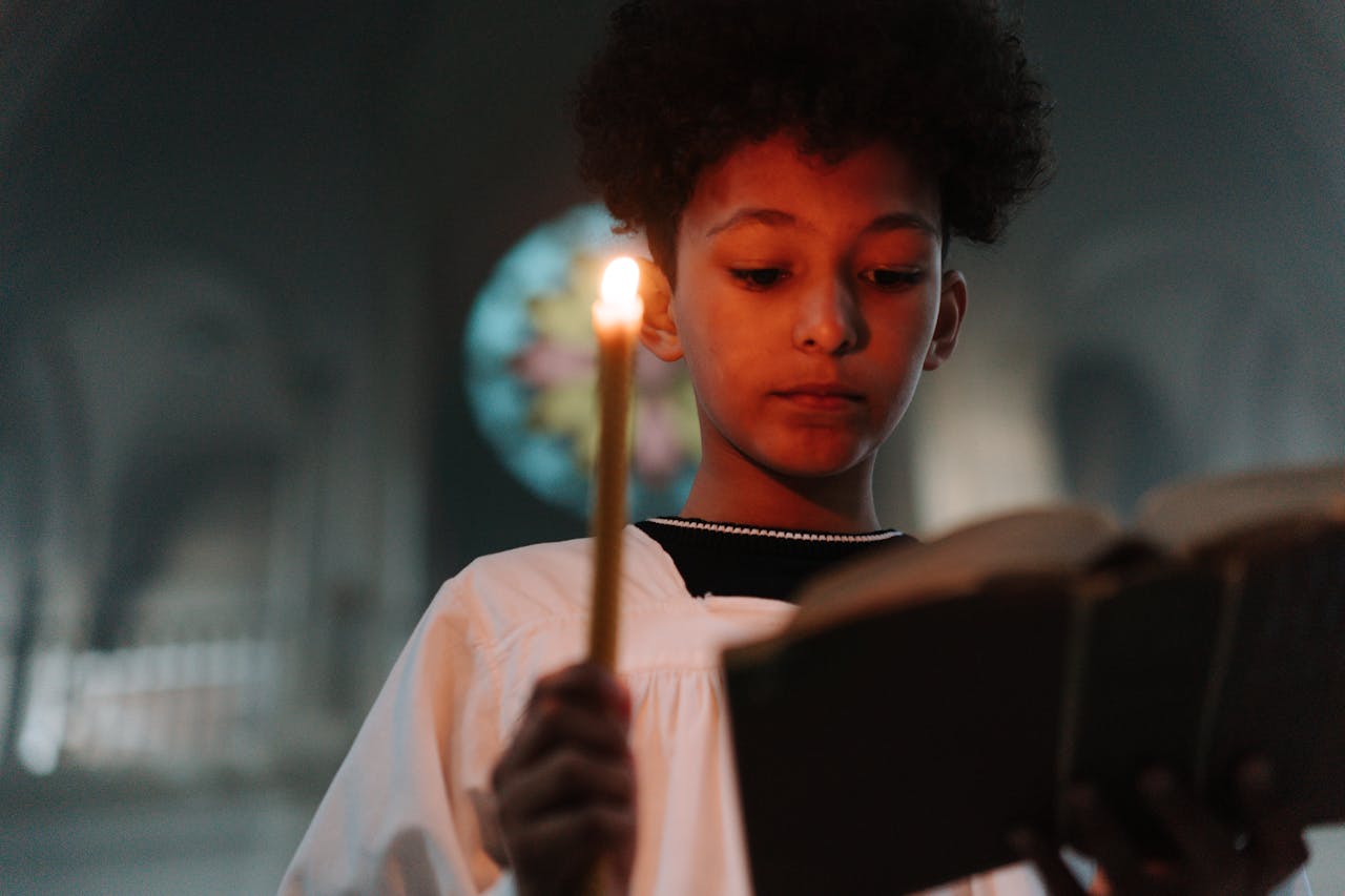 young-boy-reading-book-while-holding-a-candle-
