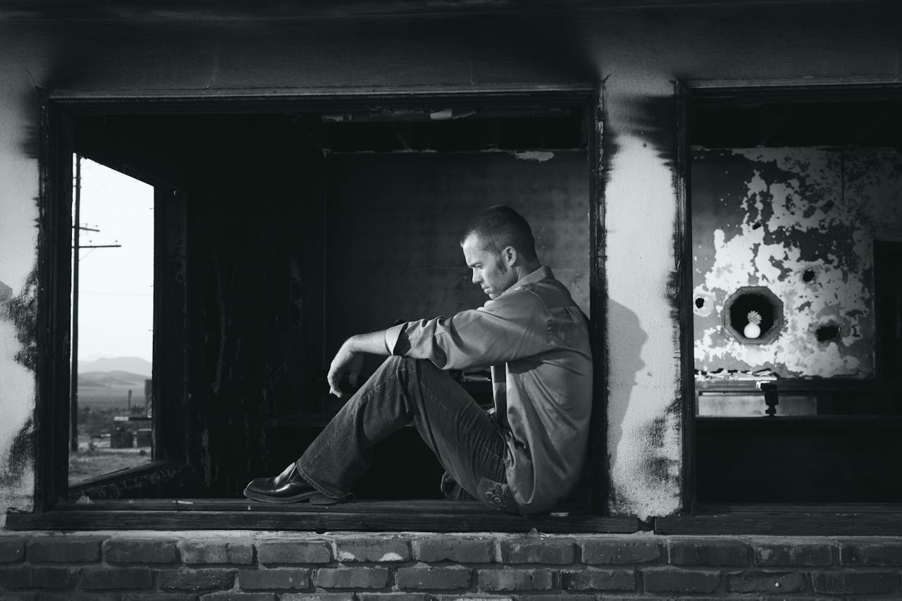 grayscale-photo-of-man-sitting