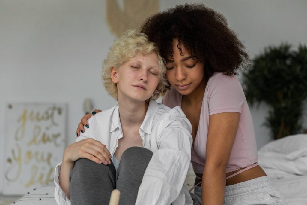 dreamy-young-diverse-girlfriends-hugging-while-resting-together-on-bed-