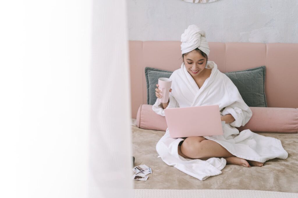 /a-woman-in-white-robe-using-a-laptop-