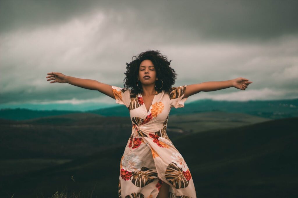 woman-in-white-and-red-floral-dress-standing-on-green-grass-field-
