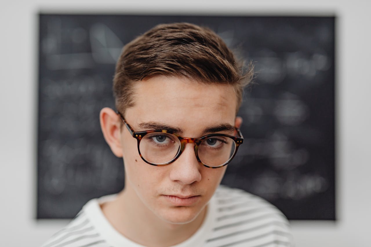 portrait-of-a-young-man-in-eyeglasses-in-front-of-a-blackboard-