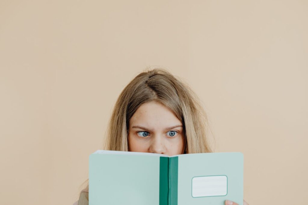 young-girl-covering-her-face-with-teal-notebook-