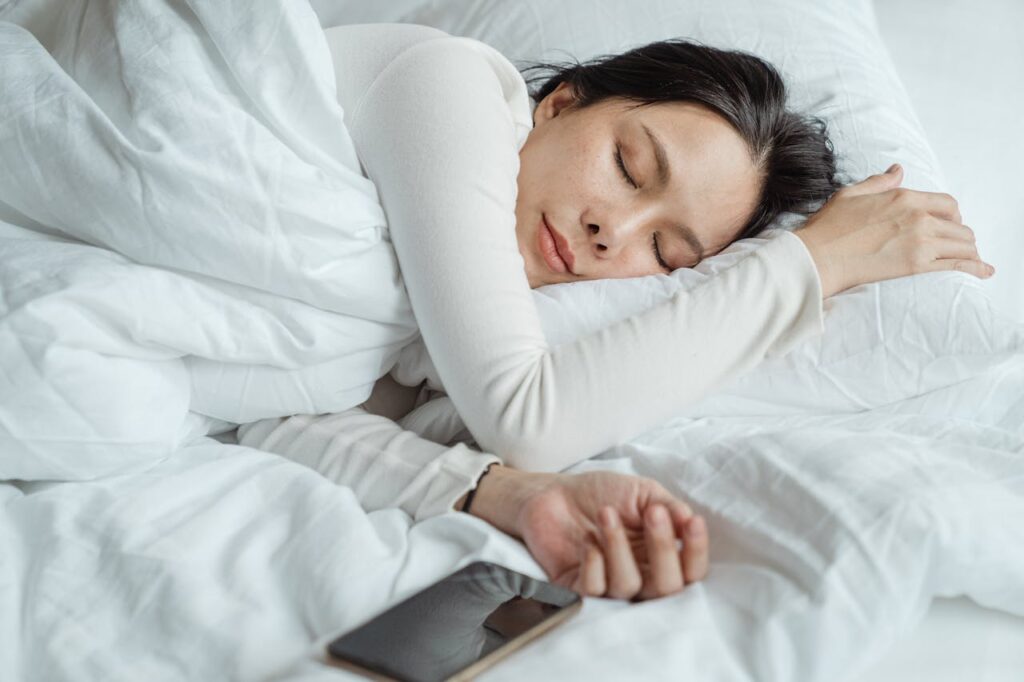woman-sleeping-in-bed-near-smartphone-