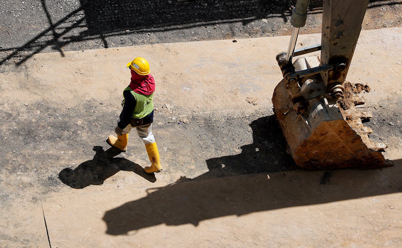 /high-angle-photo-of-person-walking-near-backhoe